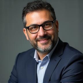 Portrait d'un homme souriant, Ahmed Benali, avec des lunettes et une posture réfléchie, symbolisant l'expertise en conformité